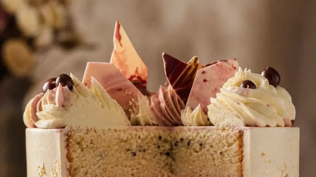 AI photos for bakeries: an AI-made concept of a celebration cake topped with chocolate shards, buttercream rosettes and gold leaf, a cake that does not exist