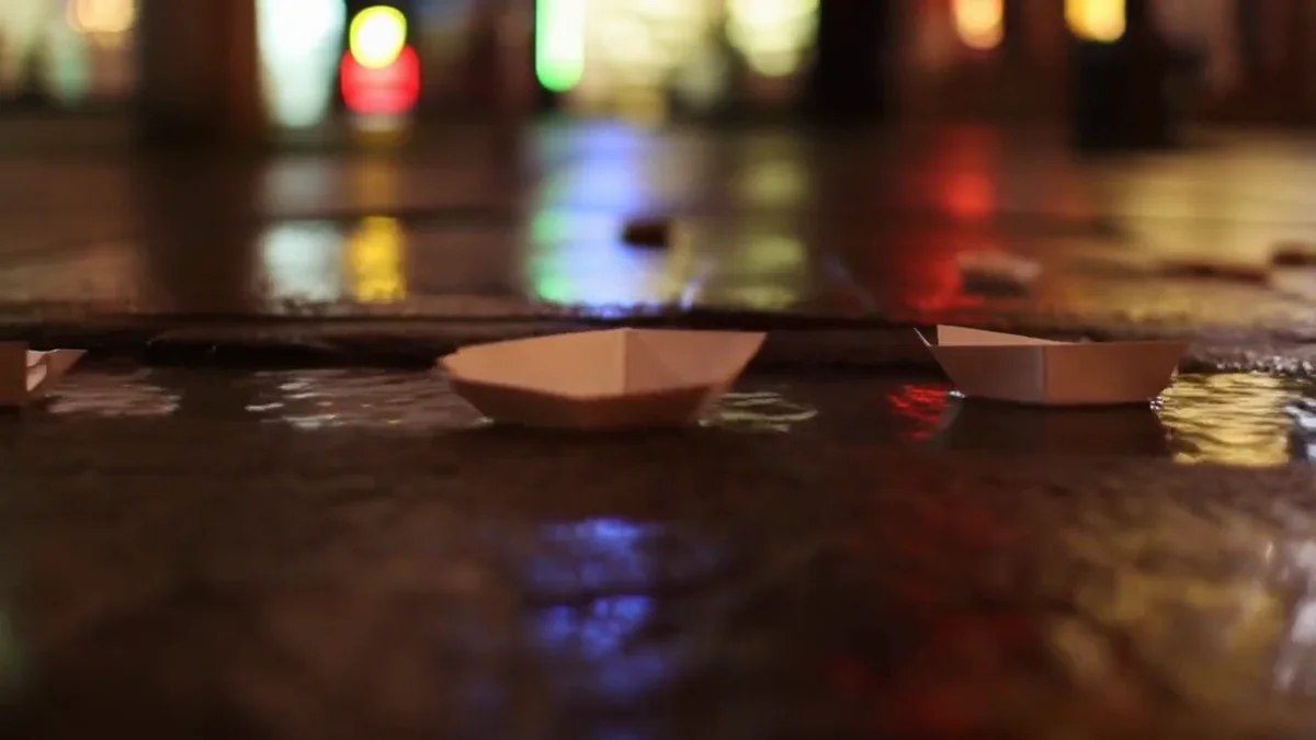 Hailuo AI review: paper boats drifting past reflected shop lights in a Hailuo 02 clip made on Lovino