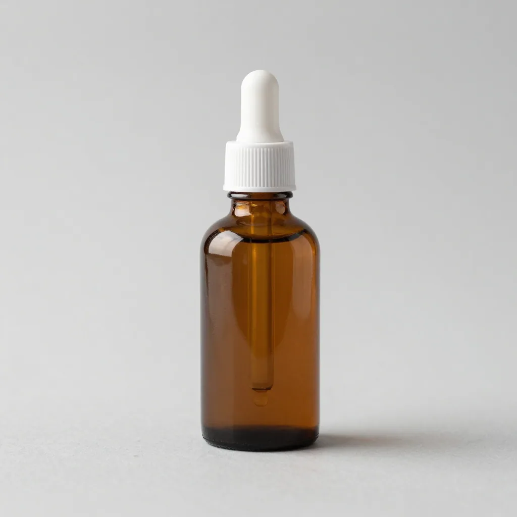 An unbranded amber glass serum bottle with a white dropper on a light grey backdrop